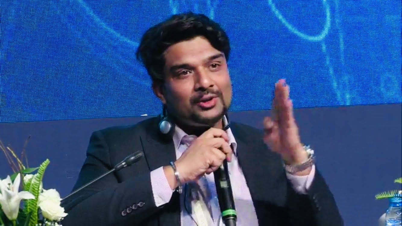 Roy Saurabh speaking on a panel, holding a microphone